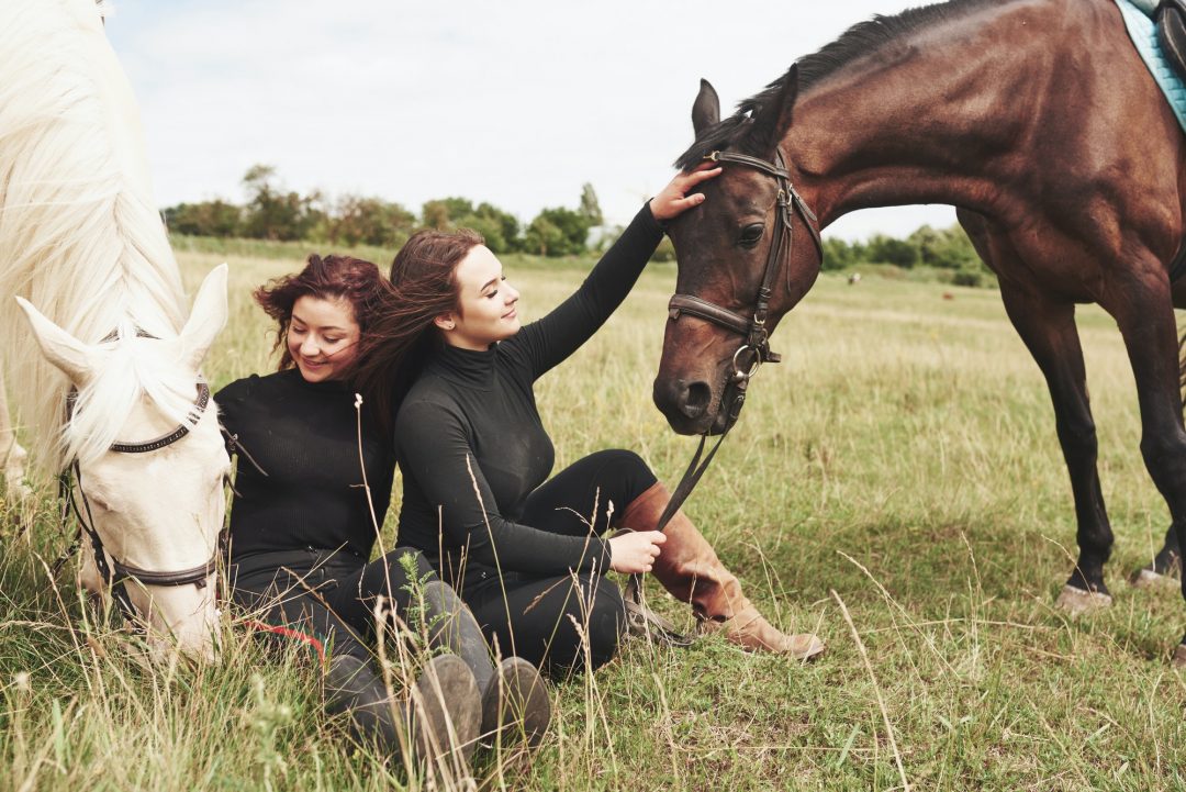 two-young-beautiful-girls-in-gear-for-riding-near-their-horses-they-love-animals.jpg